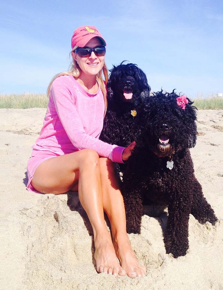 Marci sentada en la playa con sus dos perros negros